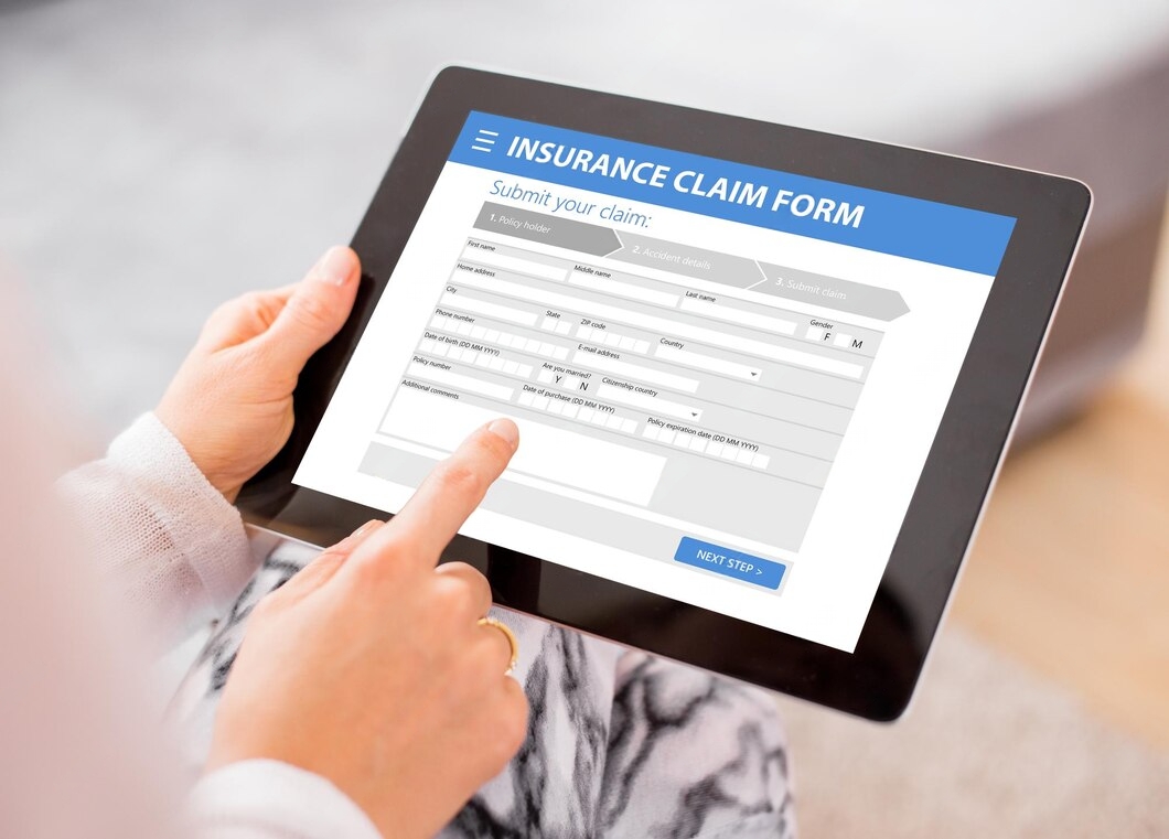 A person filling out an insurance claim form on a tablet, focusing on entering personal and policy details.